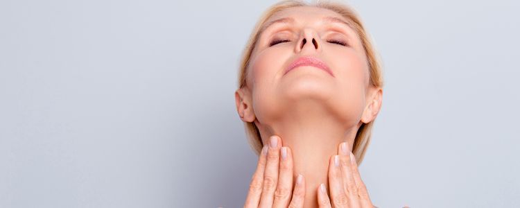 A woman is looking at her neck with her eyes closed.