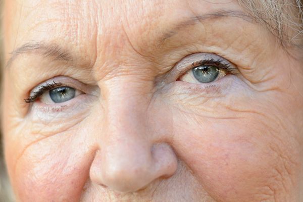 A close up of an elderly woman 's face with blue eyes.