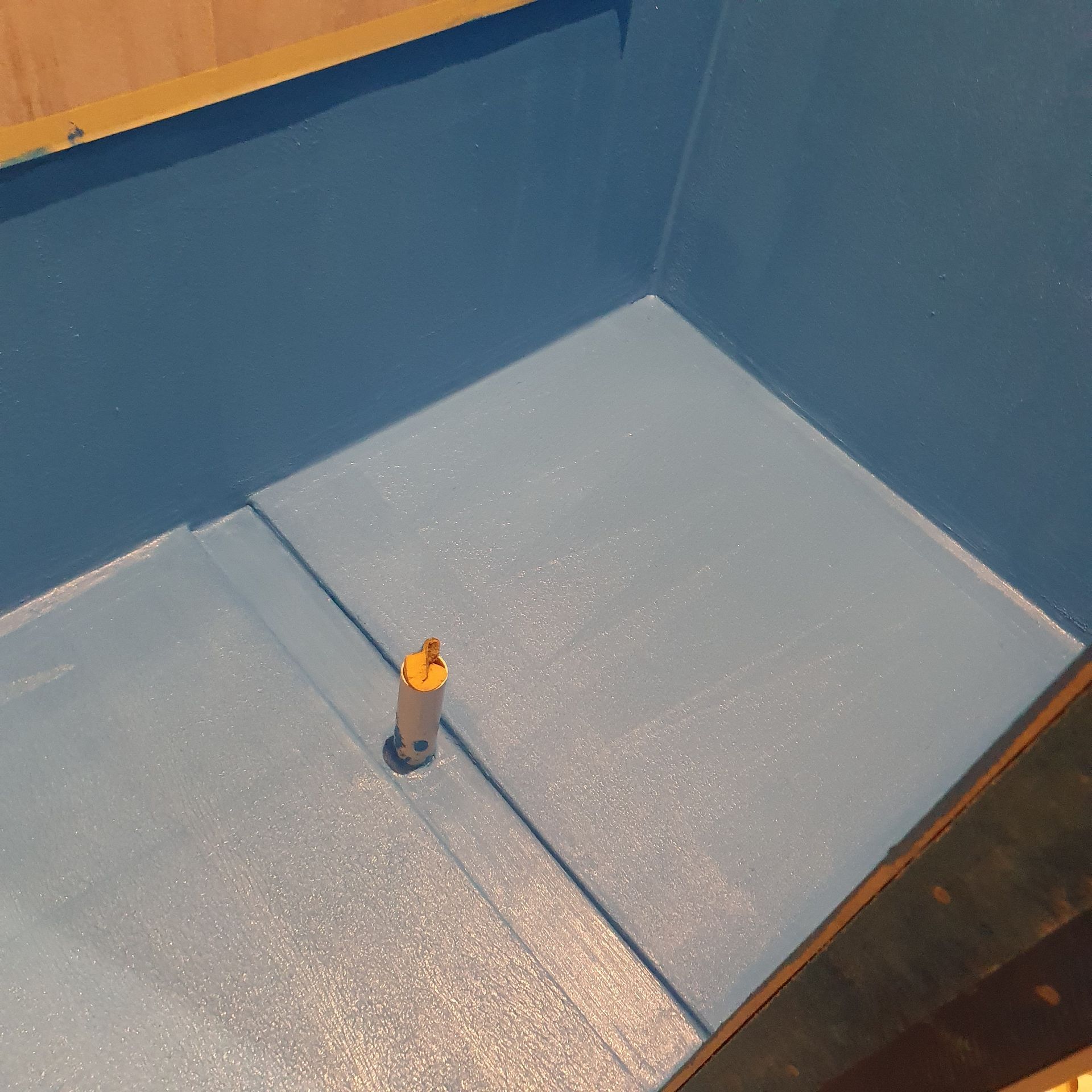 A Man Is Kneeling Down and Rolling a Roll of Waterproofing Material — Mezcon Renovations & Maintenance in Heidelberg, VIC