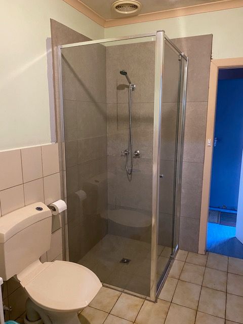 Bathroom with a square glass shower, toilet, and beige tiles — Mezcon Renovations & Maintenance in Heidelberg, VIC