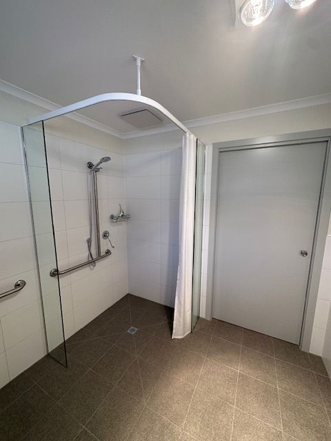 Accessible shower with a glass panel, grab bars, and a shower curtain — Mezcon Renovations & Maintenance in Heidelberg, VIC