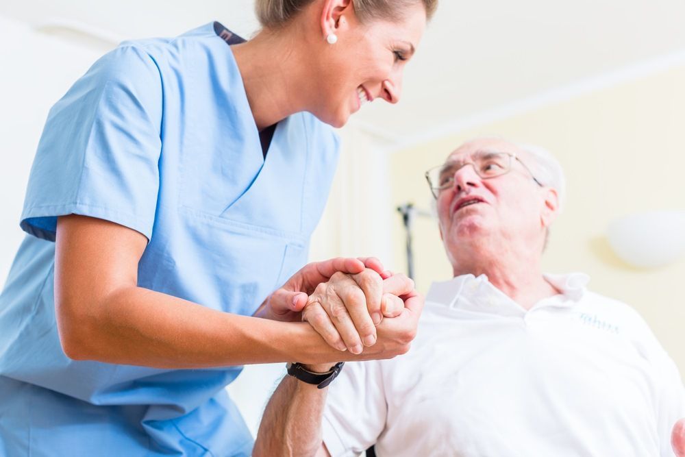 Nurse in Blue Scrubs Assisting an Elderly Man — Mezcon Renovations & Maintenance in Eaglemont, VIC