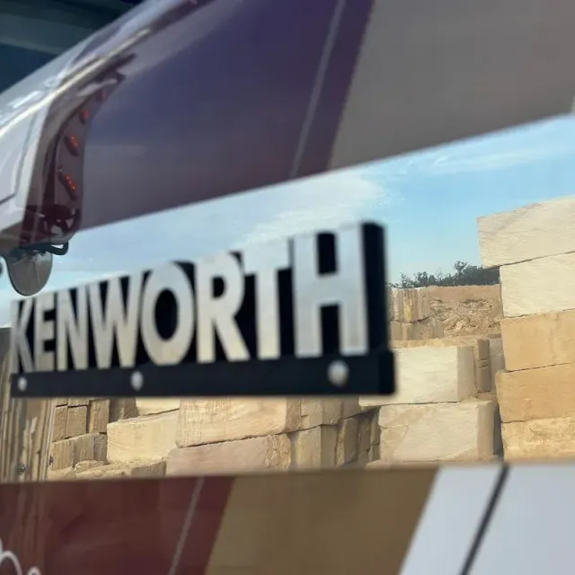 A kenworth truck has sandstone block reflected in a panel