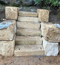 A set of sandstone stairs made out of rocks in a garden.