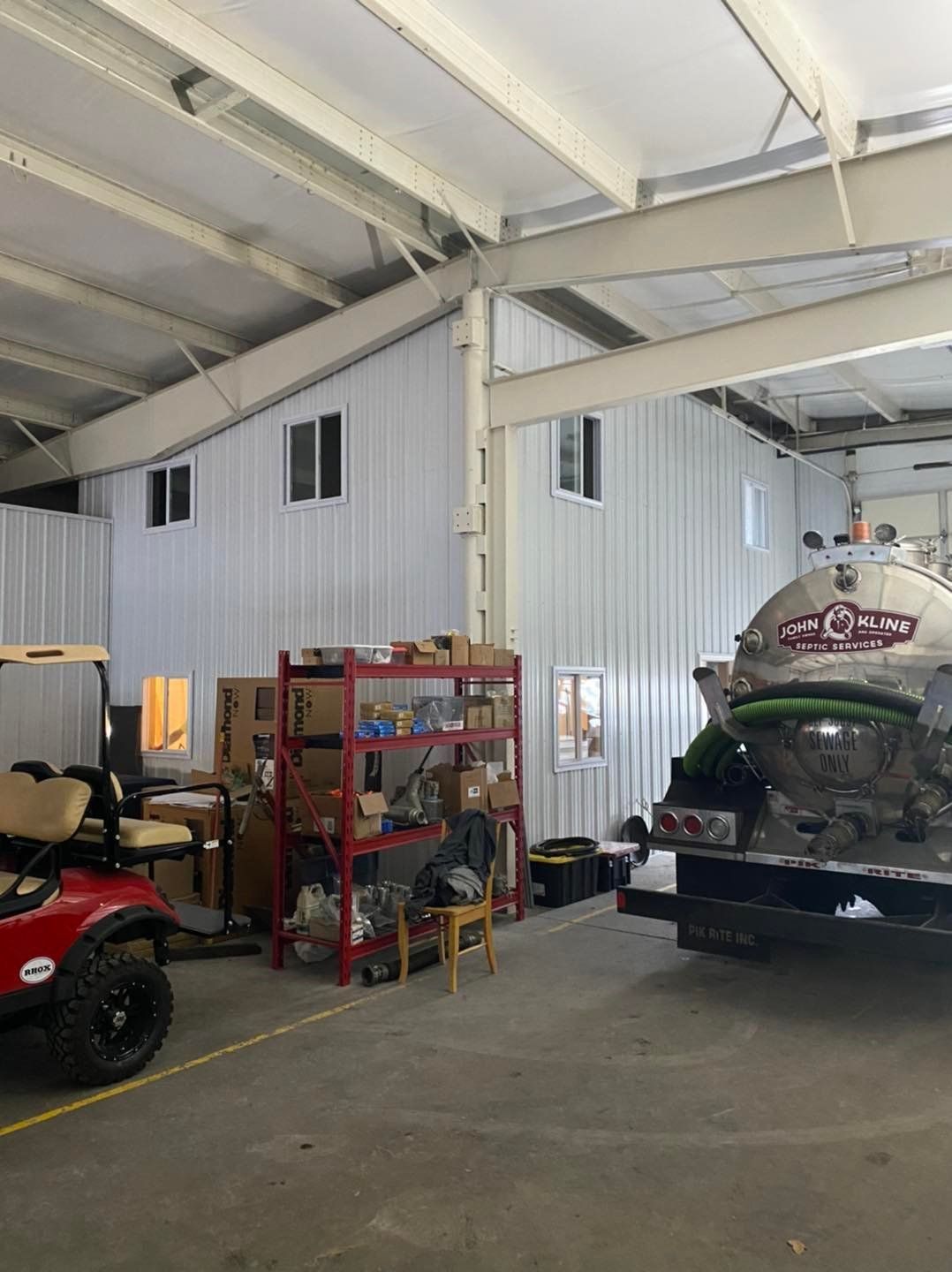 A golf cart is parked in a garage next to a truck.