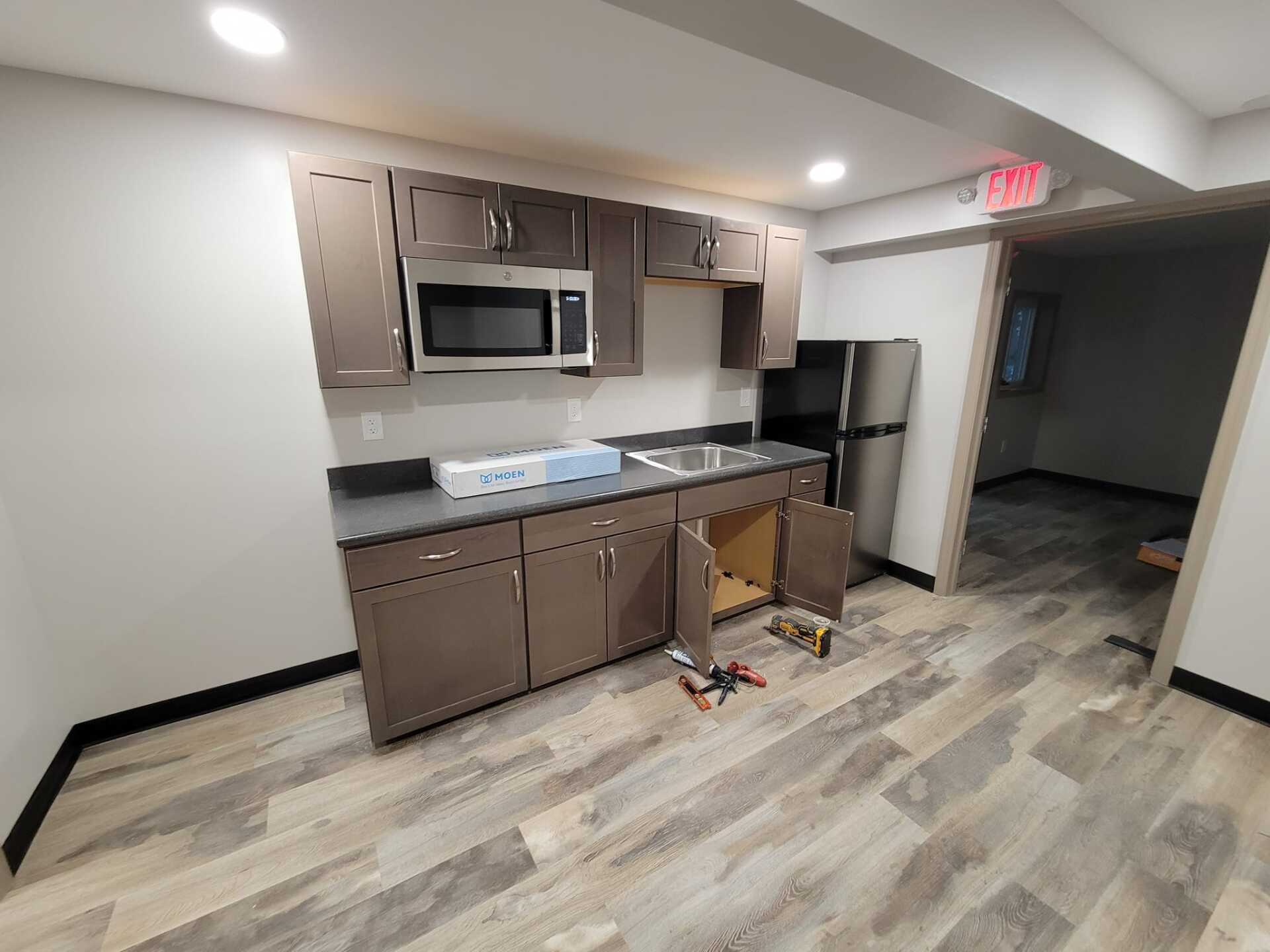 A kitchen with a refrigerator , microwave , sink and cabinets.