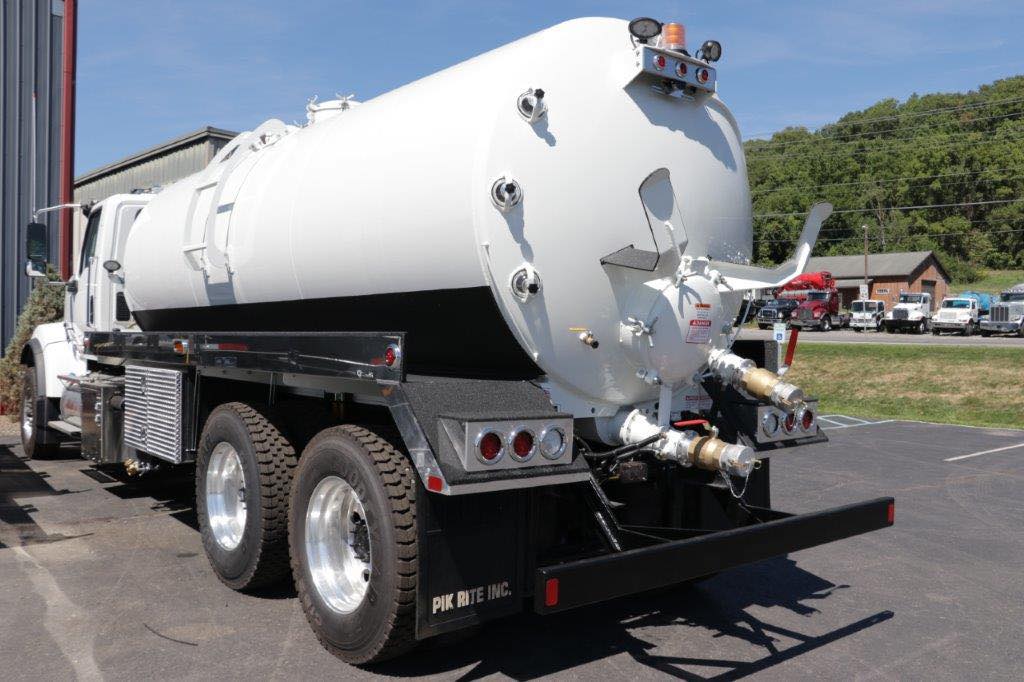 A white vacuum truck is parked in a parking lot