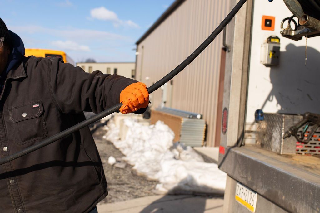septic pumping technician digging open a manhole cover