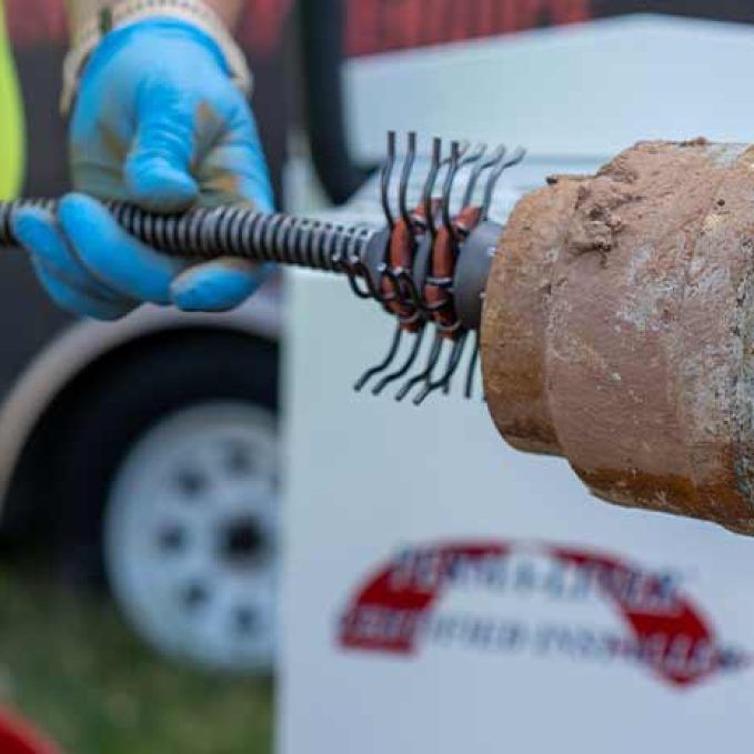 septic pumping technician digging open a manhole cover