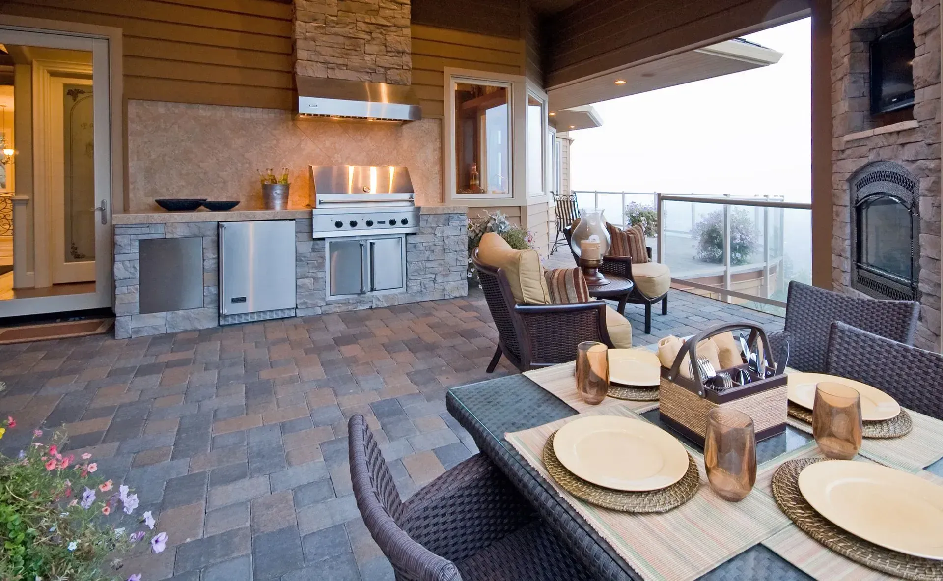 Covered patio with outdoor kitchen, dining table set, and lounge chairs overlooking a view