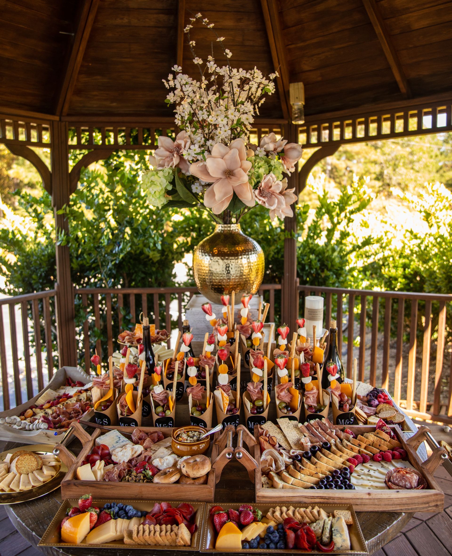Gazebo with charcuterie boards and floral arrangement.