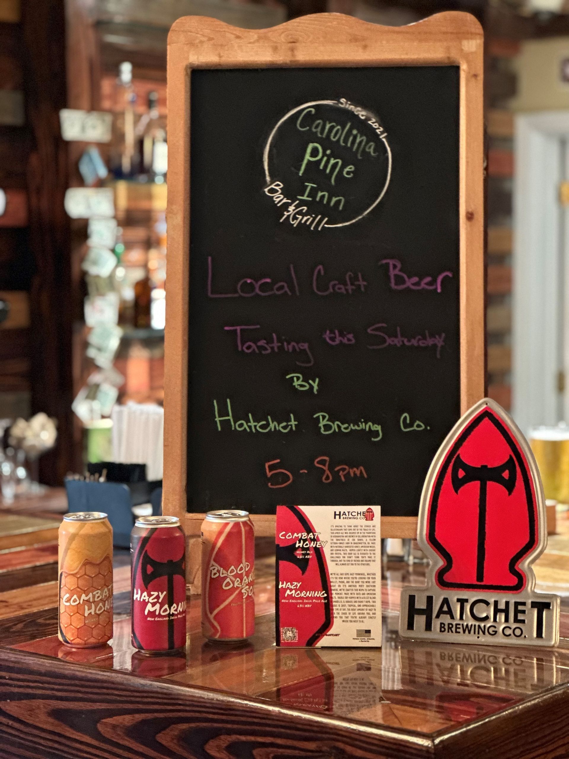 A chalkboard sign advertises a local craft beer tasting by Hatchet Brewery Co. at Carolina Pine Inn.