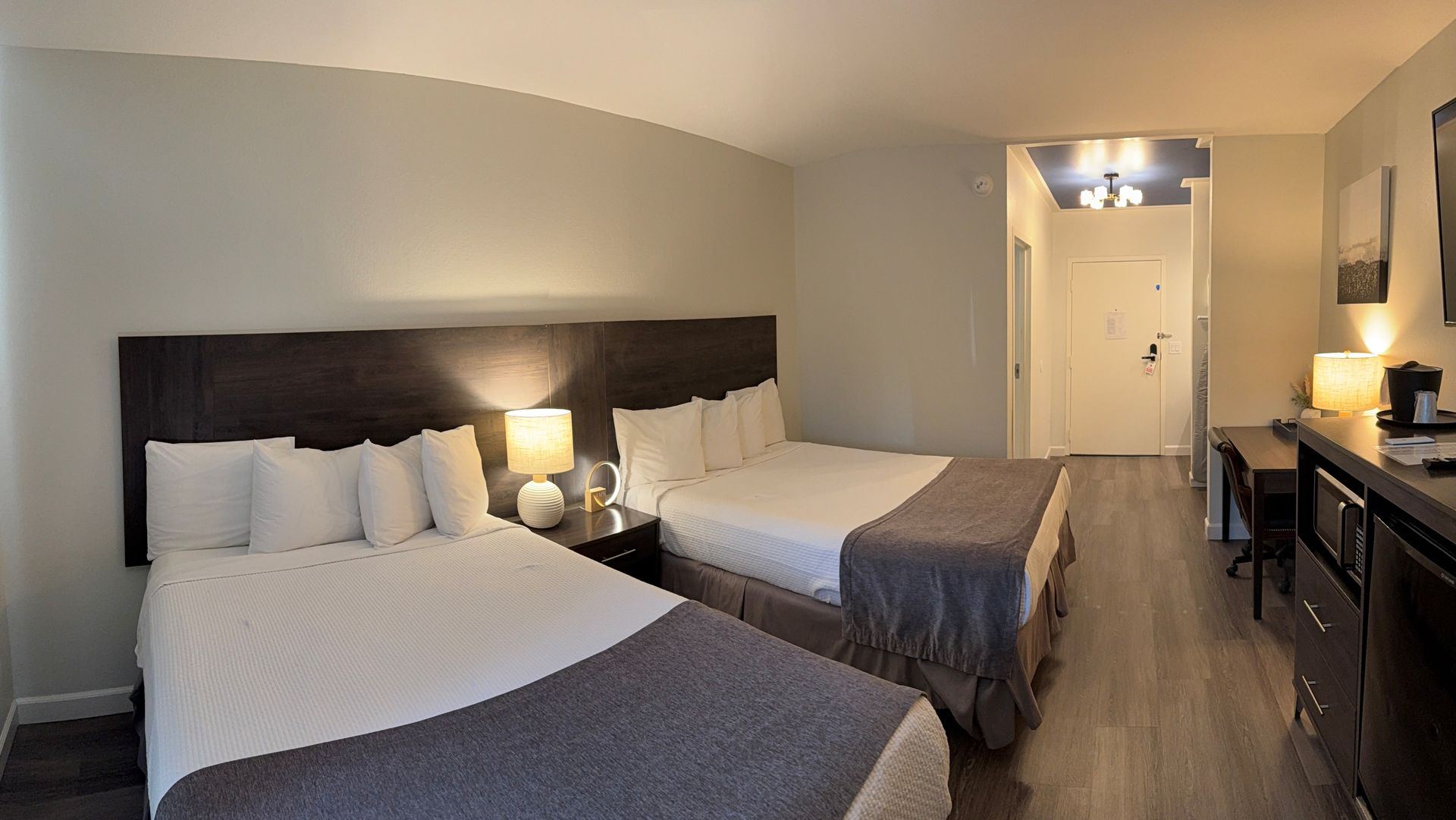 Hotel room with two beds, TV, microwave, desk, and chair.