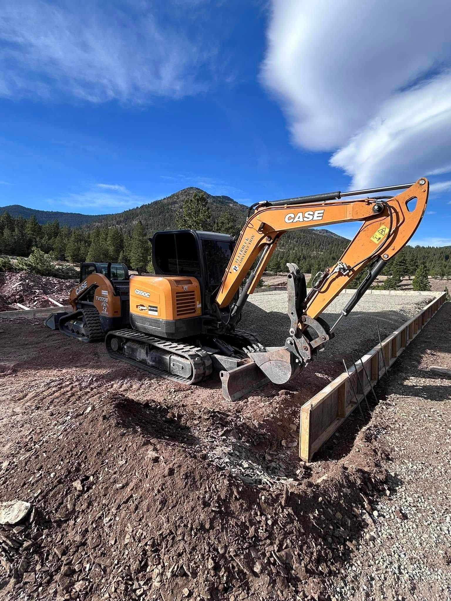 Orange excavator clearing dirt on a construction site under a blue sky.