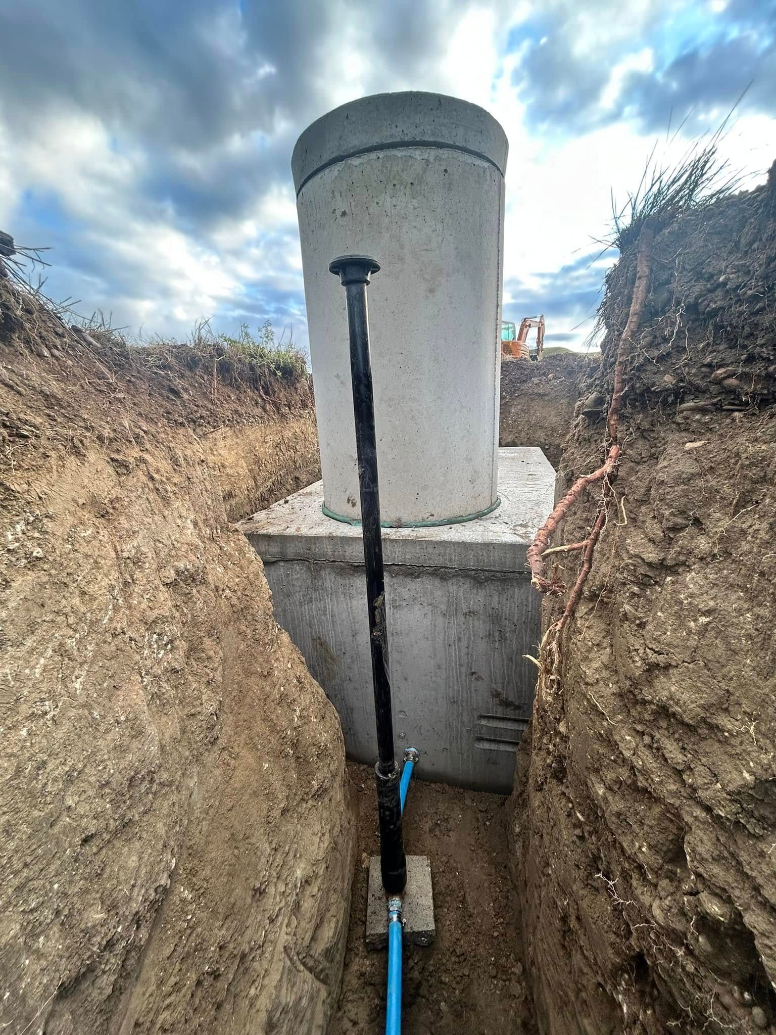 Utility pipe and vent inside a narrow trench beside a concrete structure outdoors.