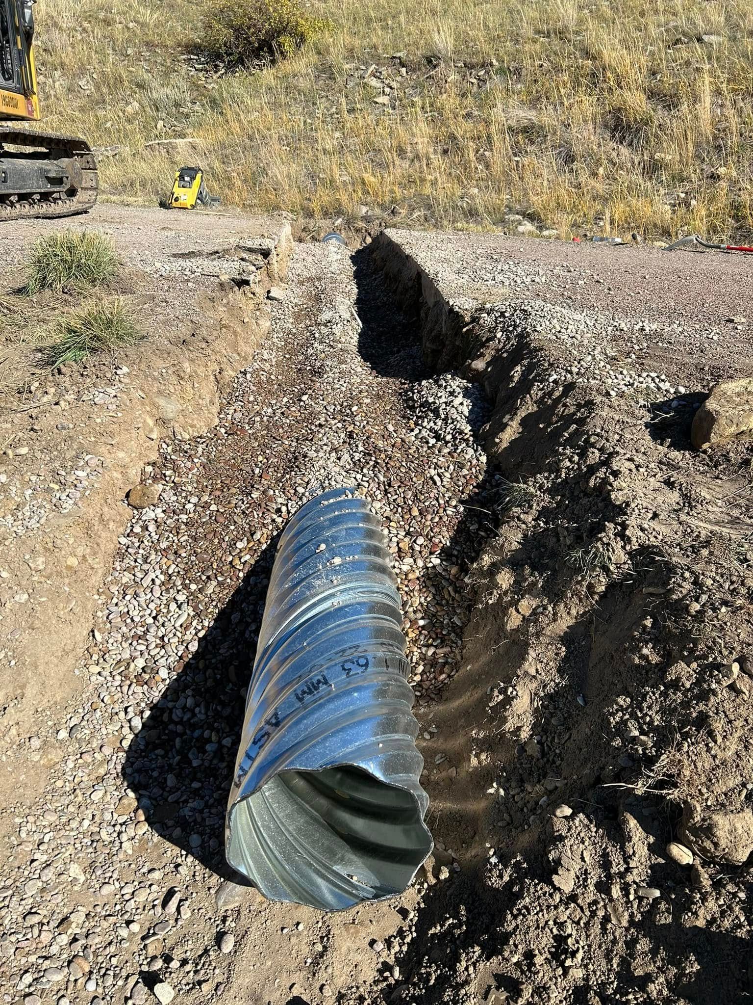 Blue corrugated pipe laid in a dirt trench at a construction site