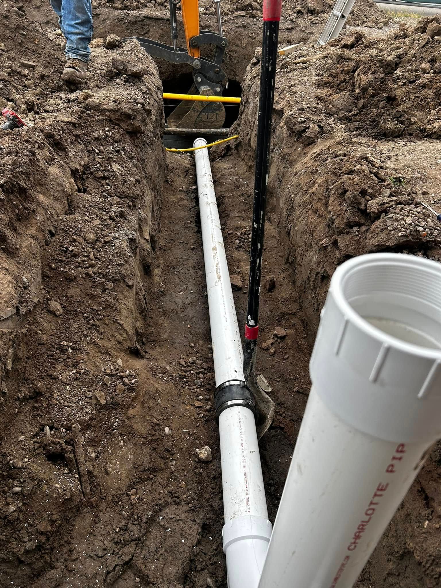 PVC pipe trench with yellow supports and muddy excavation site