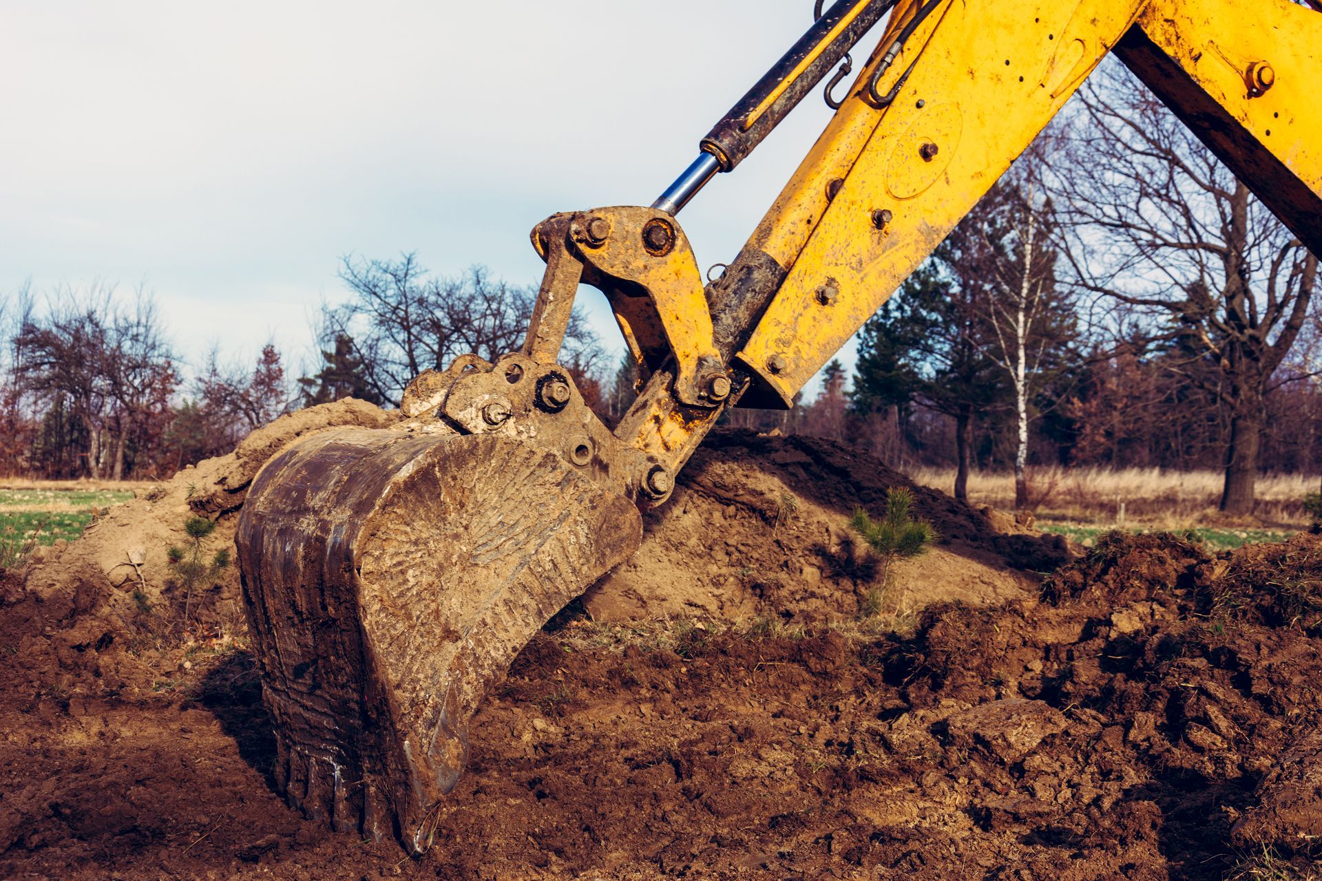 Yellow excavator scooping dirt at a muddy construction site