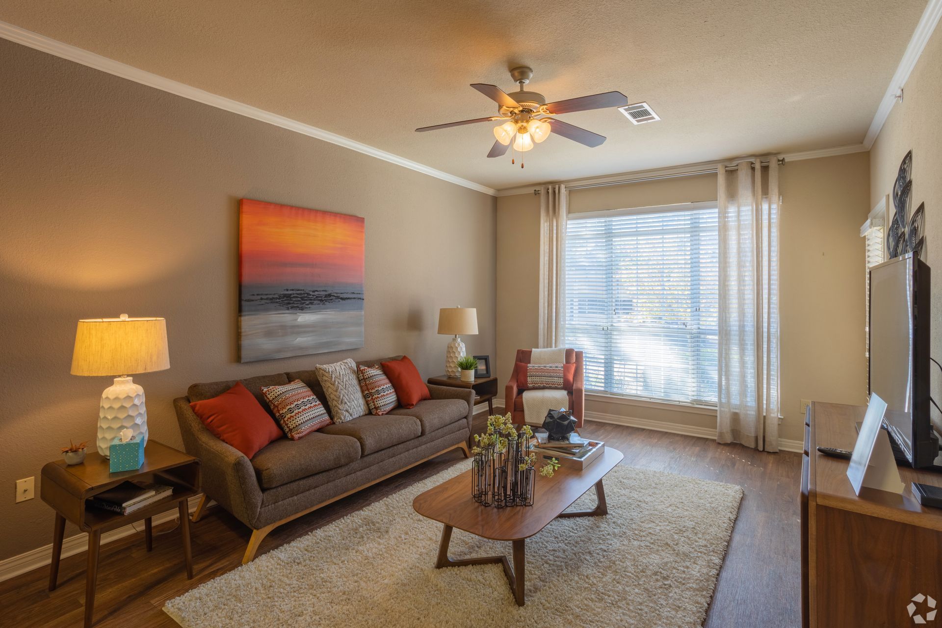 Cozy living room with gray sofa, coffee table, lamp, large window, and wall art.