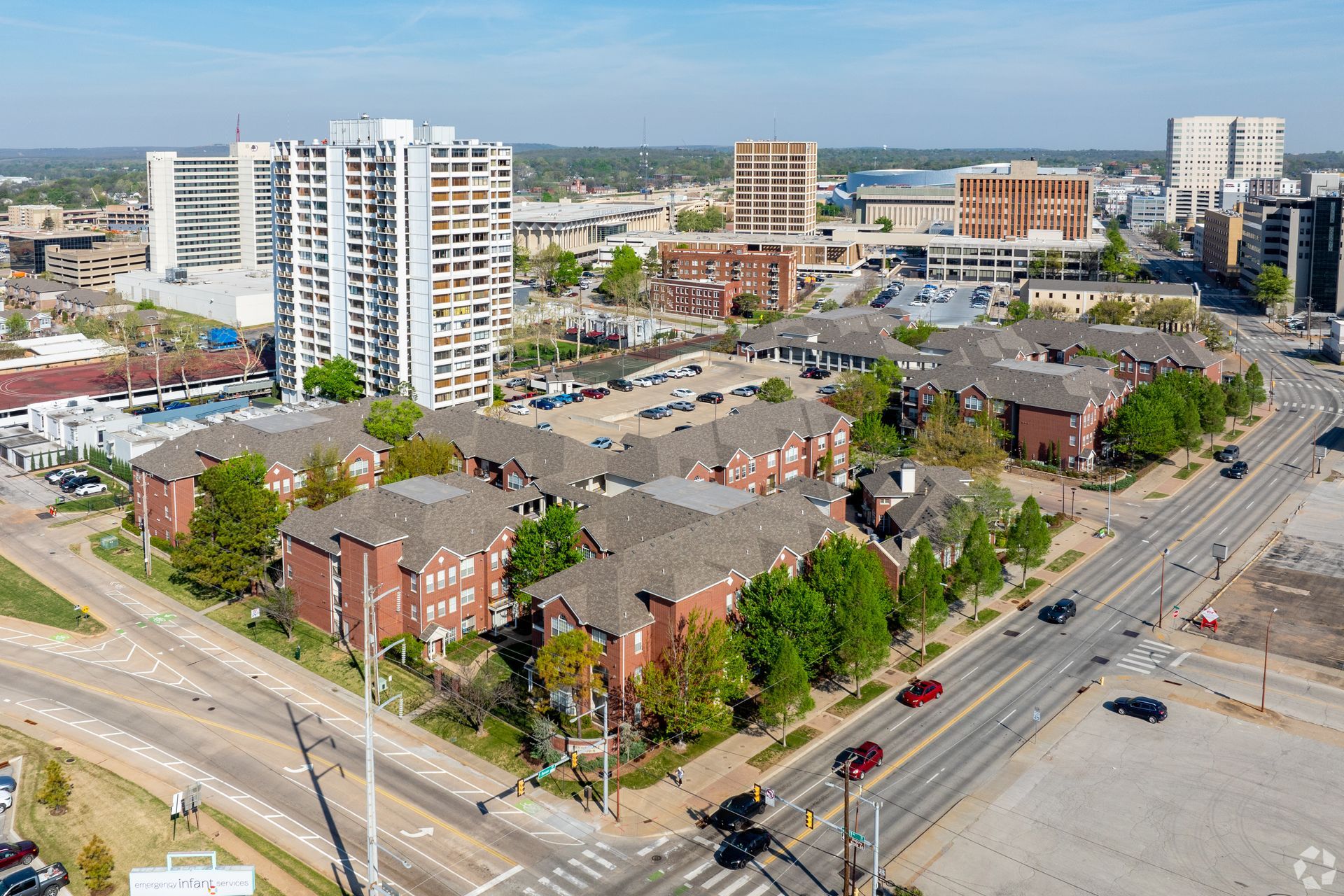 Aerial view of a city intersection with apartment buildings, shops, roads, and construction sites.