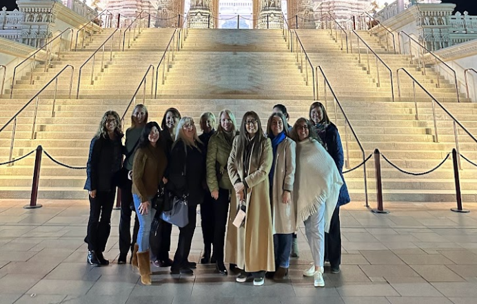 A group of women are posing for a picture in front of a building.