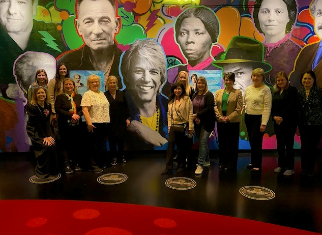 A group of people standing next to each other in front of a colorful wall.