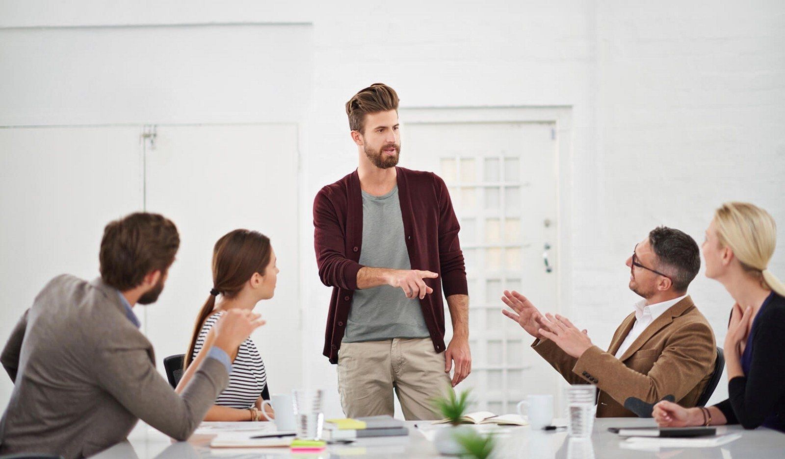 A man is giving a presentation to a group of people sitting around a table.