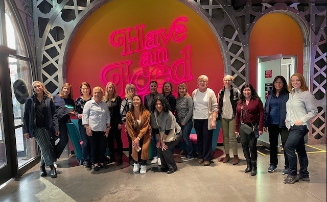 A group of people are posing for a picture in front of a neon sign.