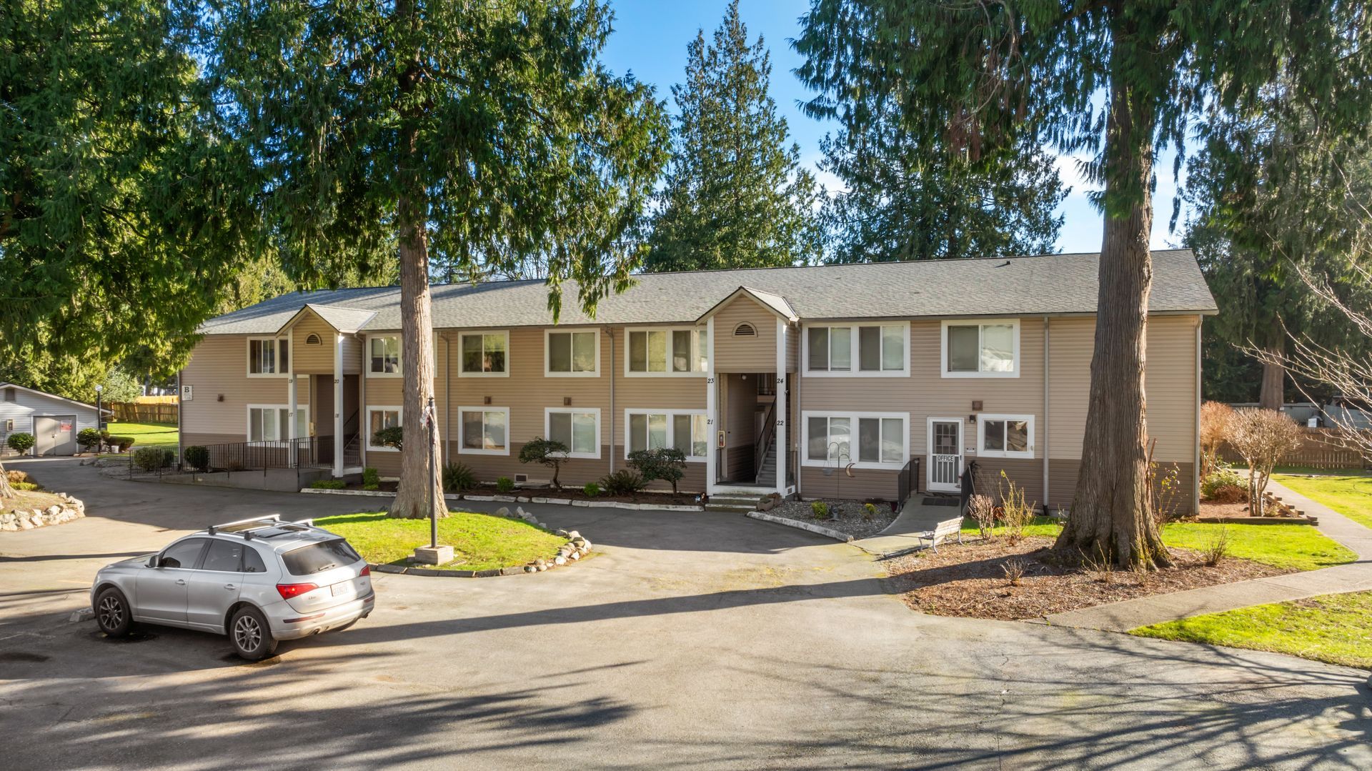 A white car is parked in front of a large apartment building.