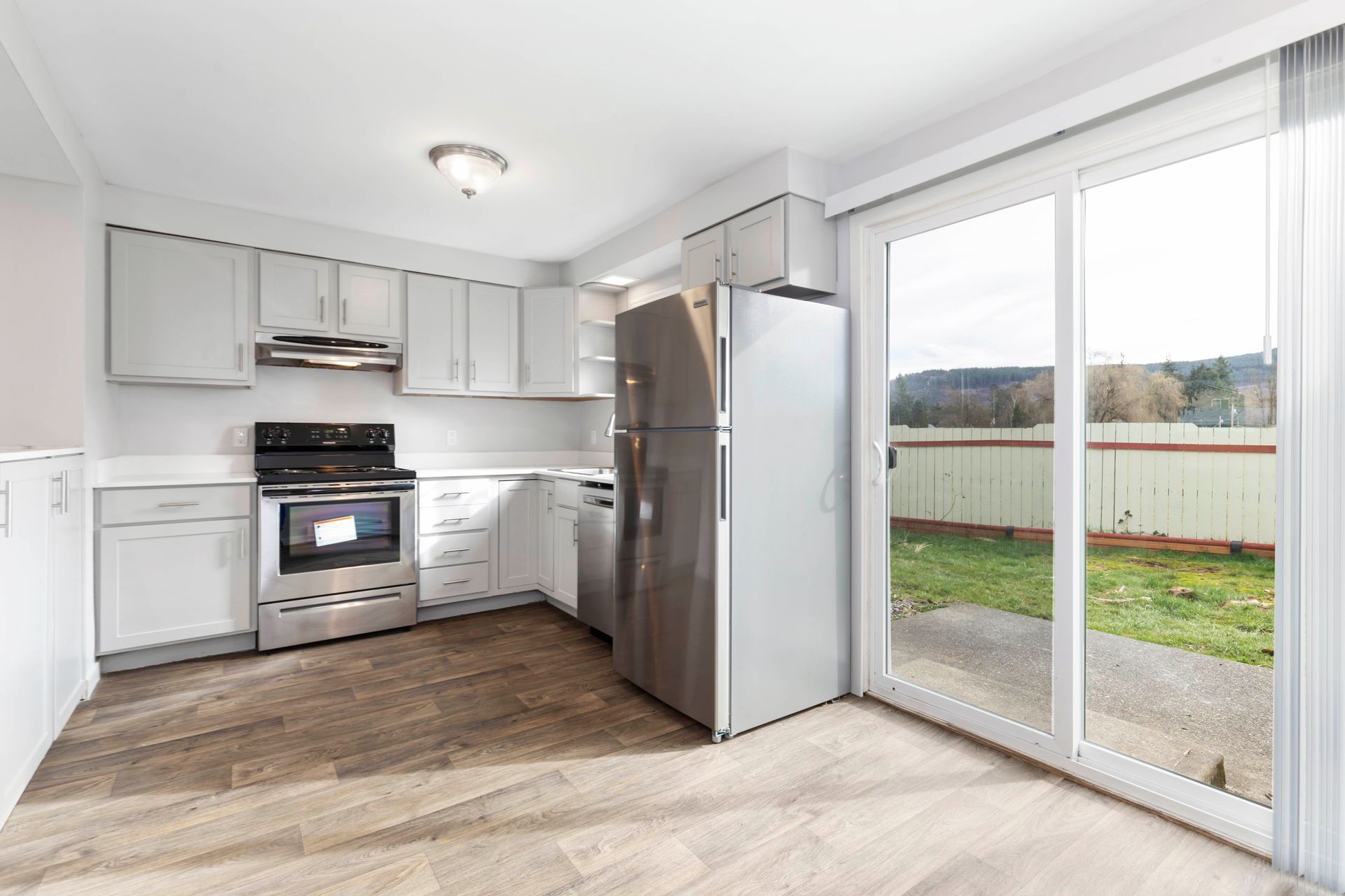 A kitchen with stainless steel appliances and a sliding glass door.