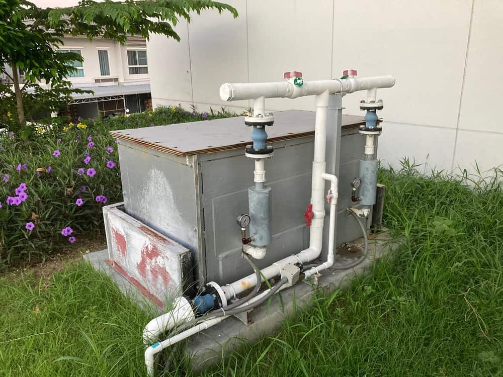 A Water Pump Is Sitting In The Grass Next To A Building — Peel Valley Plumbing In Hillvue, NSW
