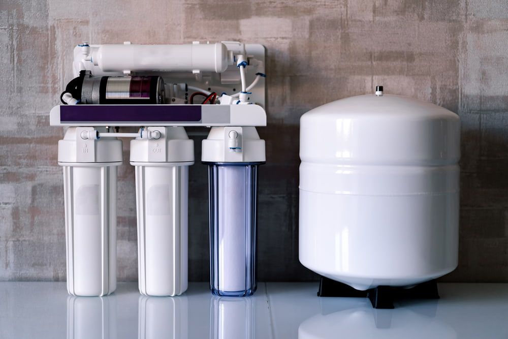 A Water Filter Is Sitting On A Counter Next To A Tank — Peel Valley Plumbing In Hillvue, NSW