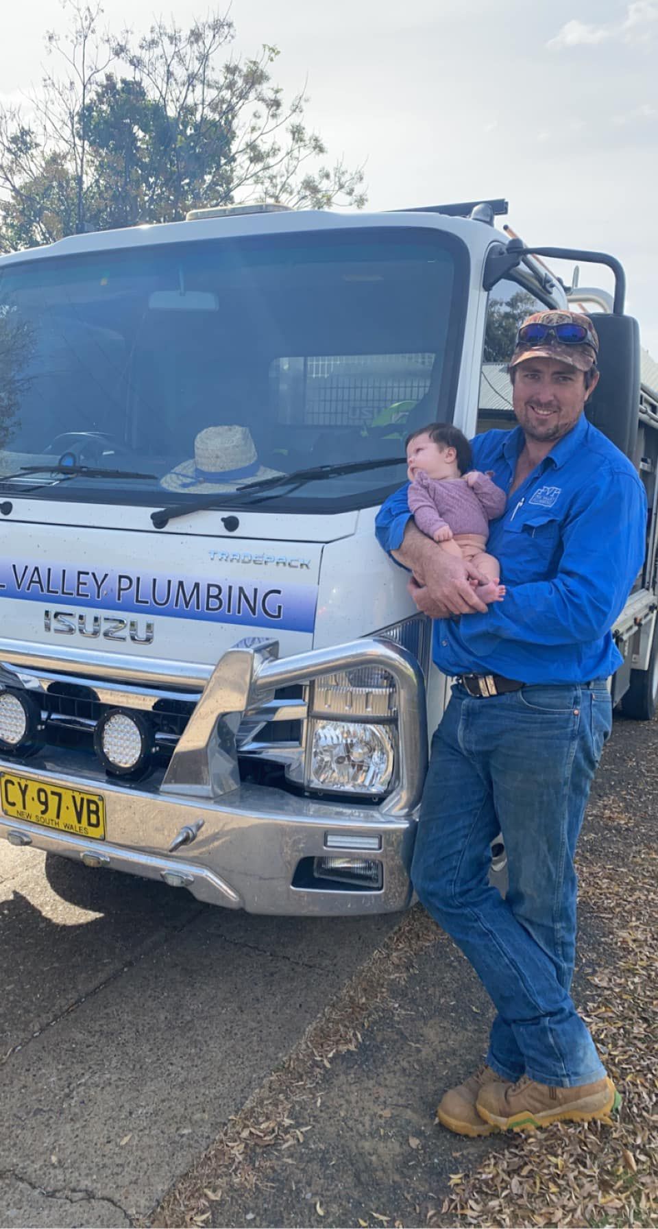 A Man Holding His Daughter In Front Of A Truck — Peel Valley Plumbing In Hillvue, NSW