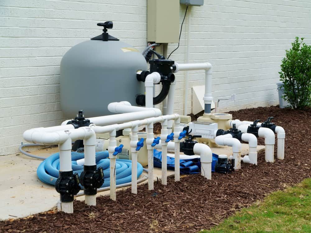 A Pool Filter Is Sitting Next To A Bunch Of Pipes — Peel Valley Plumbing In Hillvue, NSW
