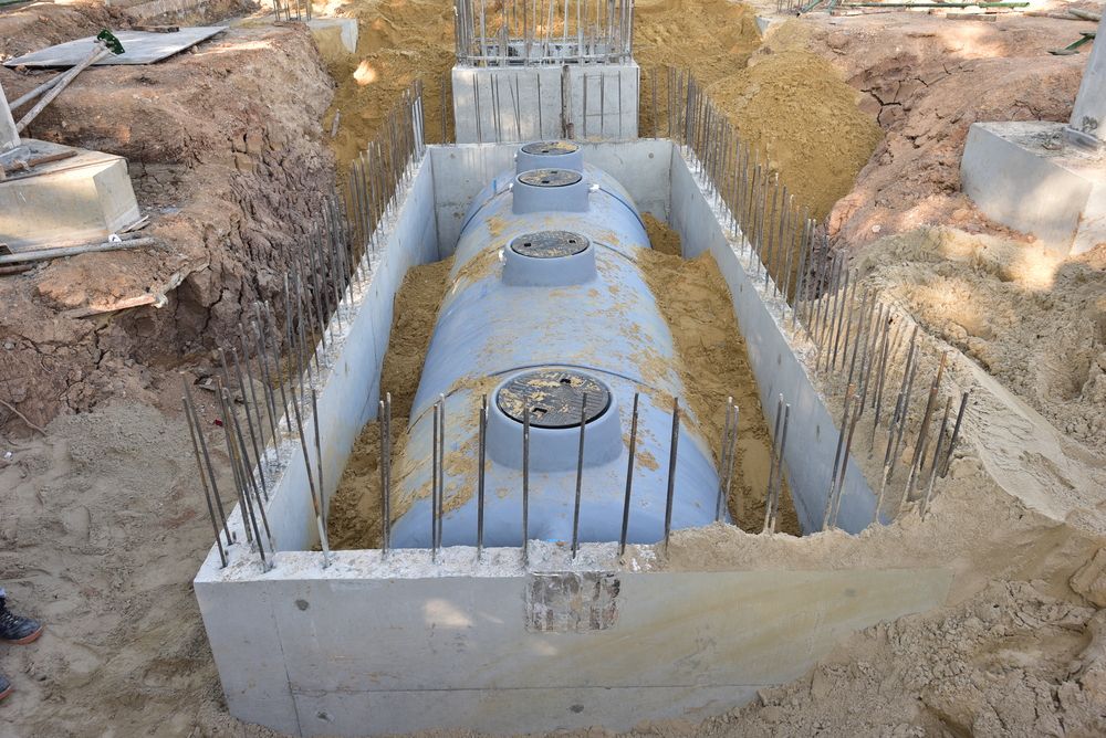 A Large Concrete Tank is Sitting in the Dirt in a Trench — Peel Valley Plumbing In Hillvue, NSW