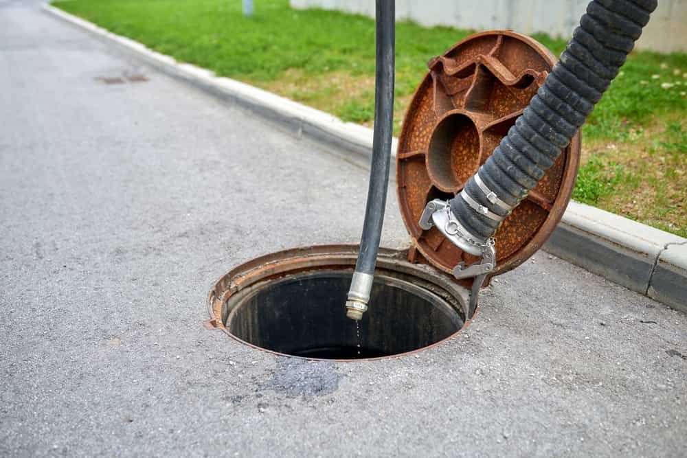A Manhole Cover Is Open And A Hose Is Coming Out Of It — Peel Valley Plumbing In Hillvue, NSW