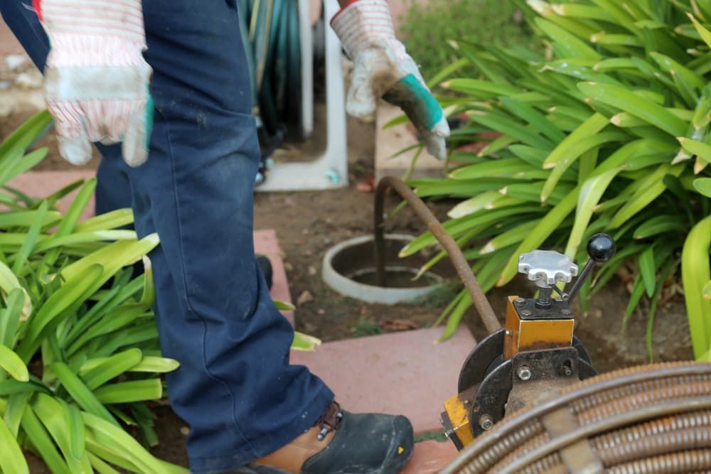 A Person Is Using A Hose To Clean A Drain In A Garden — Peel Valley Plumbing In Hillvue, NSW
