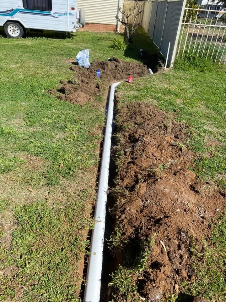 A White Pipe is Being Installed in the Dirt in a Yard — Peel Valley Plumbing In Hillvue, NSW