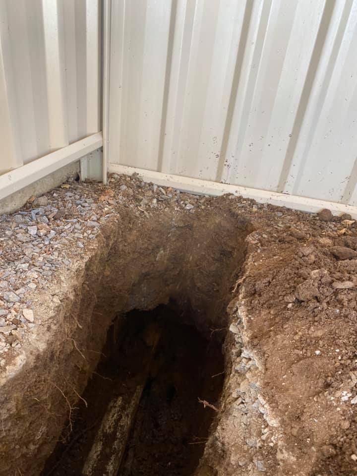 A Hole in the Ground Next to a Metal Fence — Peel Valley Plumbing In Hillvue, NSW
