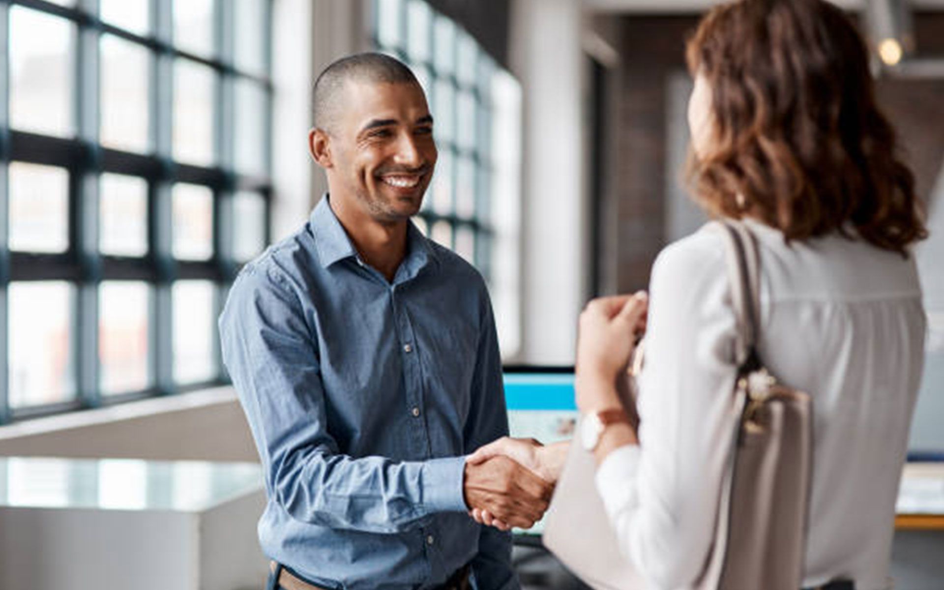 A man and a woman are shaking hands in an office.