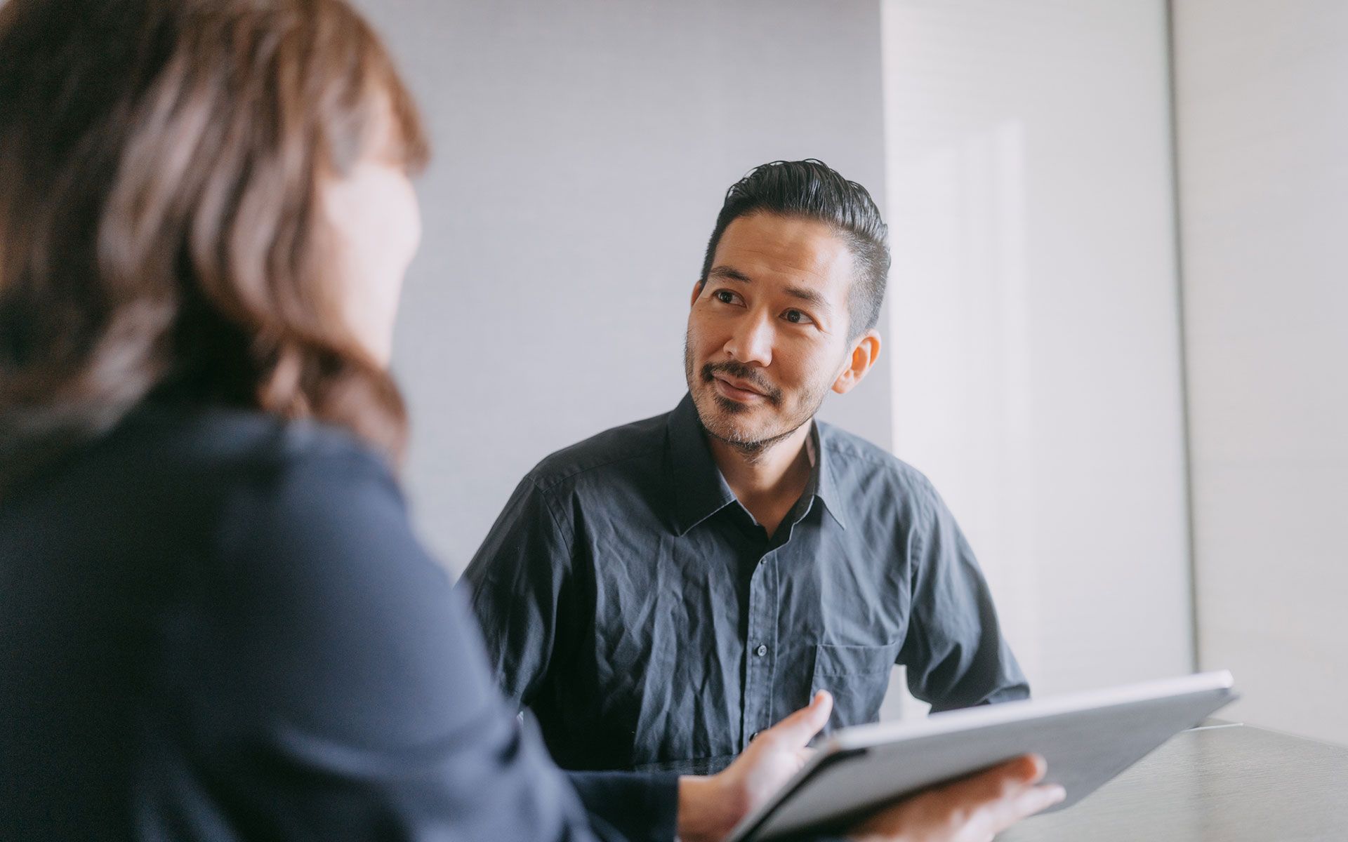 A man is holding a tablet and talking to a woman.
