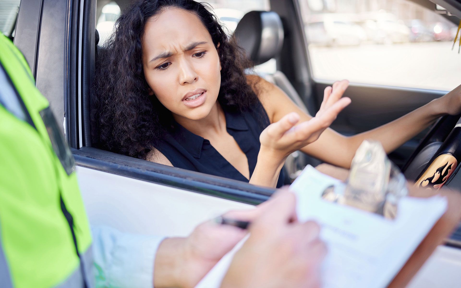 A woman is sitting in a car talking to a police officer.