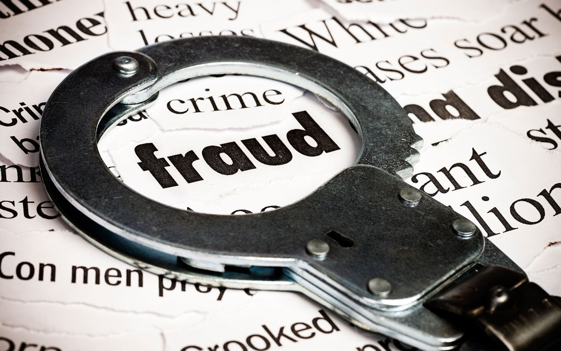 A pair of handcuffs on top of a newspaper with the word fraud on it