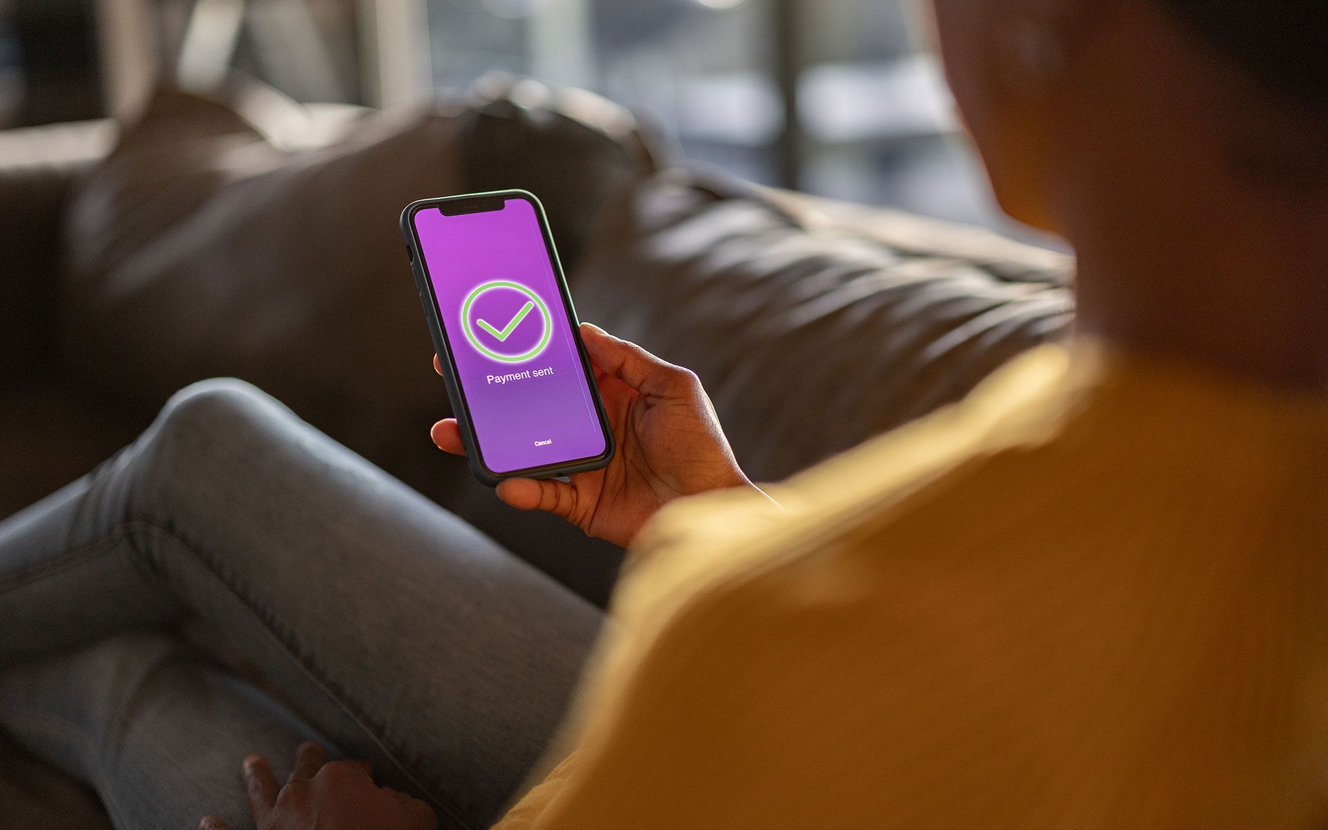 A person is sitting on a couch holding a cell phone.