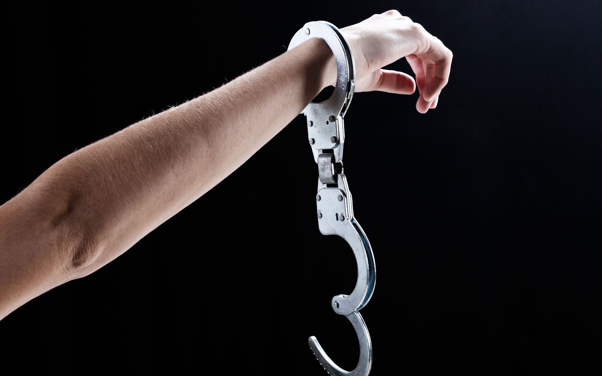 A person is holding a pair of handcuffs on their wrist.