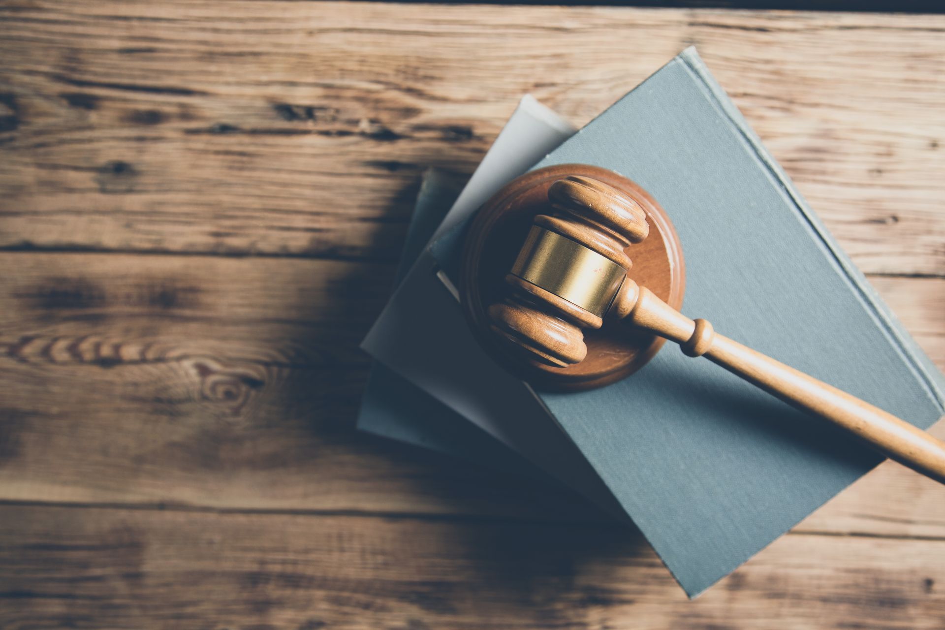Gavel resting on a blue book atop a wooden table