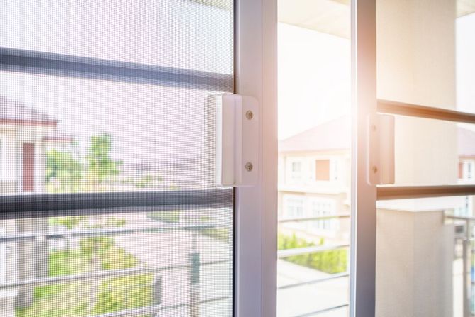 Finestra soleggiata con tende trasparenti che si affaccia su una tranquilla strada residenziale e sulle case