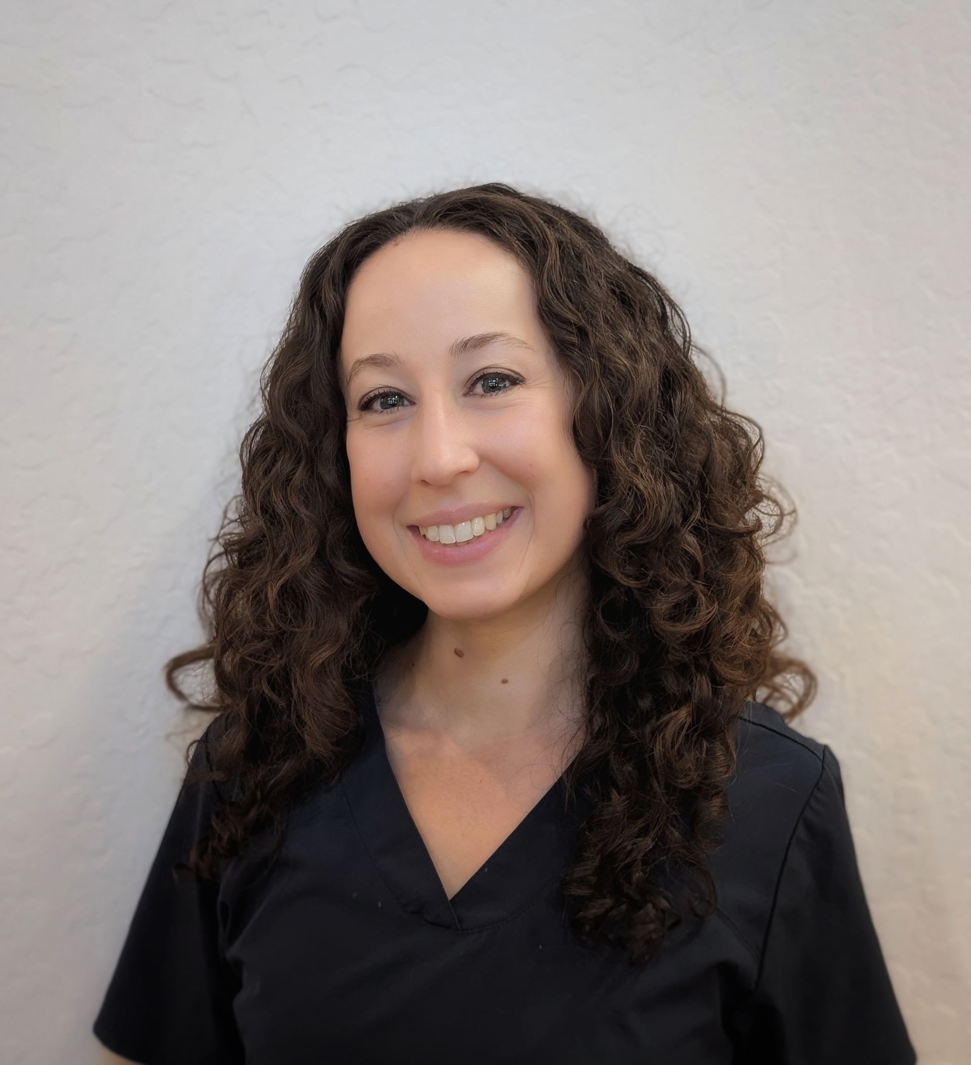 a woman with curly hair is smiling for the camera .