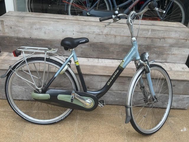 Blauw-zwarte Gazelle Nederlandse fiets met spatborden en bagagedrager.