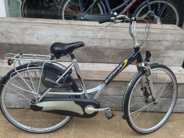 Zwarte en zilverkleurige Batavus-fiets met bagagedrager, buiten geparkeerd.